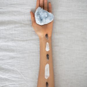 A serene arrangement of crystals on an arm over a soft linen backdrop, emphasizing holistic healing.
