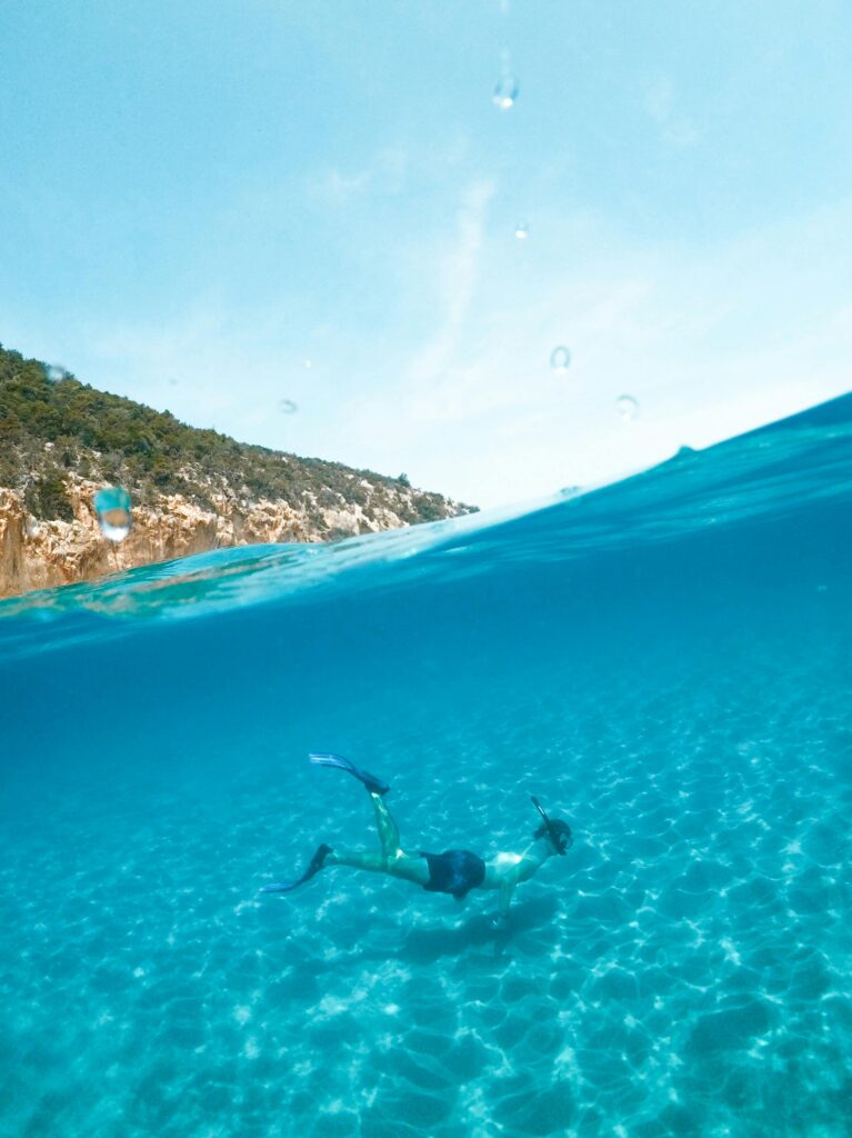 Man snorkeling in the clear blue waters of Sardinia, Italy, enjoying underwater adventure.